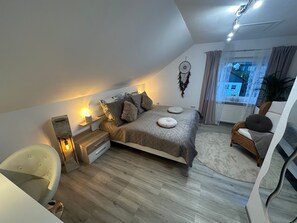 Ein Schlafzimmer mit Bett, Nachttisch, Stuhl und Blick ins Freie.