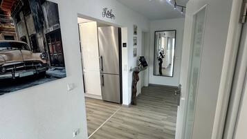 A modern kitchen with a stainless steel refrigerator, a wooden floor, and a wall-mounted sign that reads 'Kitchen.'