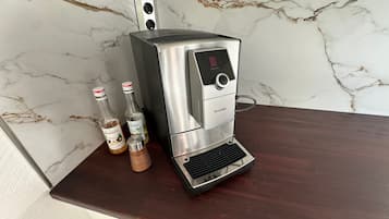 Una màquina de cafè d'acer inoxidable amb pantalla digital, damunt un taulell de fusta.