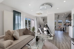 A modern living room with a sofa, a glass coffee table, and a stationary exercise bike.