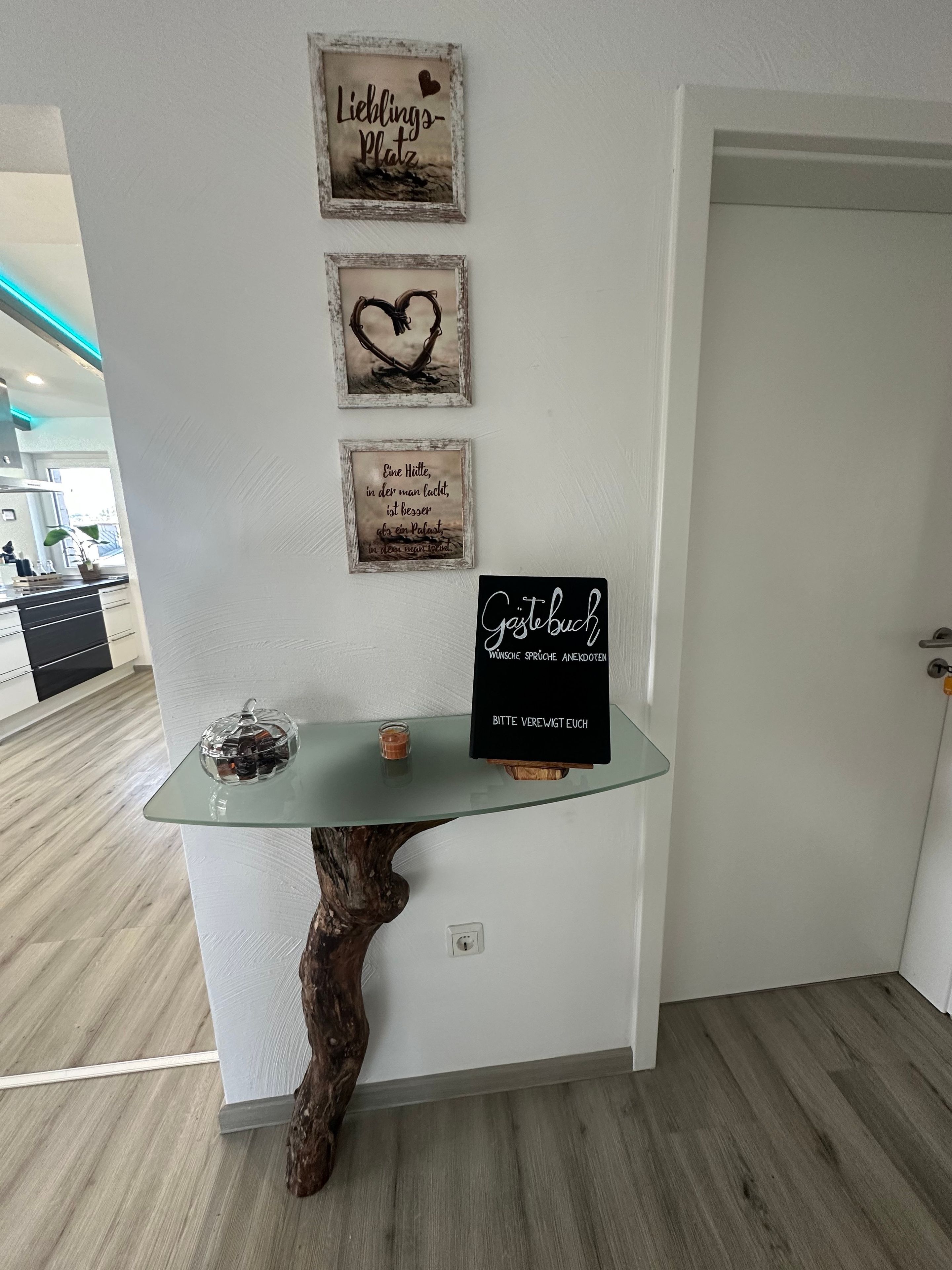 Een modern interieur met een tafel met glazen blad, houten onderstel en decoratieve objecten.