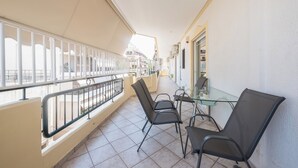 A balcony with a glass table and chairs, a railing, and a view of the street. - Vrbo Property (Athina)