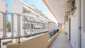 A corridor with a tiled floor, white railings, and a view of neighboring buildings. - Vrbo Property (Athina)