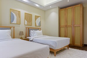 Ein Hotelzimmer mit zwei Betten, einem Nachttisch mit Lampe und einem großen Kleiderschrank mit gewebtem Muster.