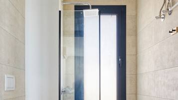 Un baño moderno con inodoro, cabina de ducha de vidrio y tocador con lavabo.