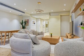 A modern living room with a sofa set, a coffee table, and a TV on a stand. - Vesta - Luxury APT - 4BR - New Cairo III (New Cairo)