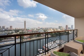 Ein Balkon mit Blick auf eine Stadtlandschaft, darunter ein markanter Turm und ein Fluss mit Booten.