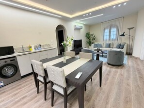 Ein modernes Wohnzimmer mit Essbereich, einer Sofagarnitur, einem Couchtisch und einem Fernseher.