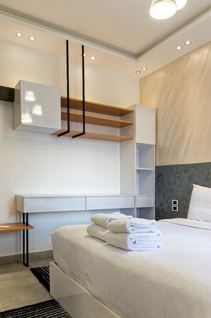 A modern bedroom with a large bed, built-in shelving, and a minimalist design. - Vesta - Luxury APT - 2BR - Village Gate (New Cairo)