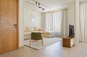 Ein modernes Wohnzimmer mit einer Couch, einem Sessel, einem Fernseher und einer Holzkabine.