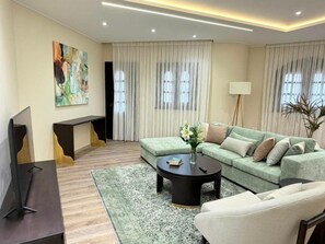 A modern living room with a sofa, coffee table, and a TV. - Vesta - Luxury APT - 2BR - South Teseen II (New Cairo)