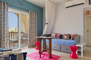 Ein Zimmer mit einem Bett, einem Tisch, einem Stuhl, einer Couch und einem Fenster mit Vorhängen.