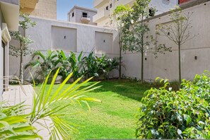 A courtyard with a grassy area, potted plants, and a building facade. - Luxury Duplex - 3BR - Zayed City II (6th of October City)