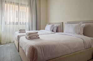 A hotel room with two beds, each with a headboard, and a large window with sheer curtains. - Vesta - Luxury APT - 3BR - Zayed City IV (6th of October City)