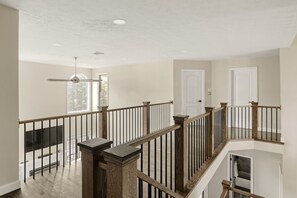 A multi-level interior with a wooden staircase, a ceiling fan, and a view of the outdoors through a window. - Spa House, Sauna, Pool, Arcade, Theater, Pickleball Court, & More! (Mount Union)
