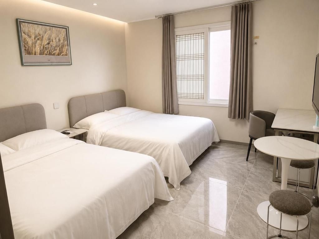 A hotel room with two beds, a dining table, and a chair.