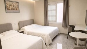 Una habitación de hotel con dos camas, una mesa de comedor y una silla.