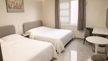 A hotel room with two beds, a dining table, and a chair.
