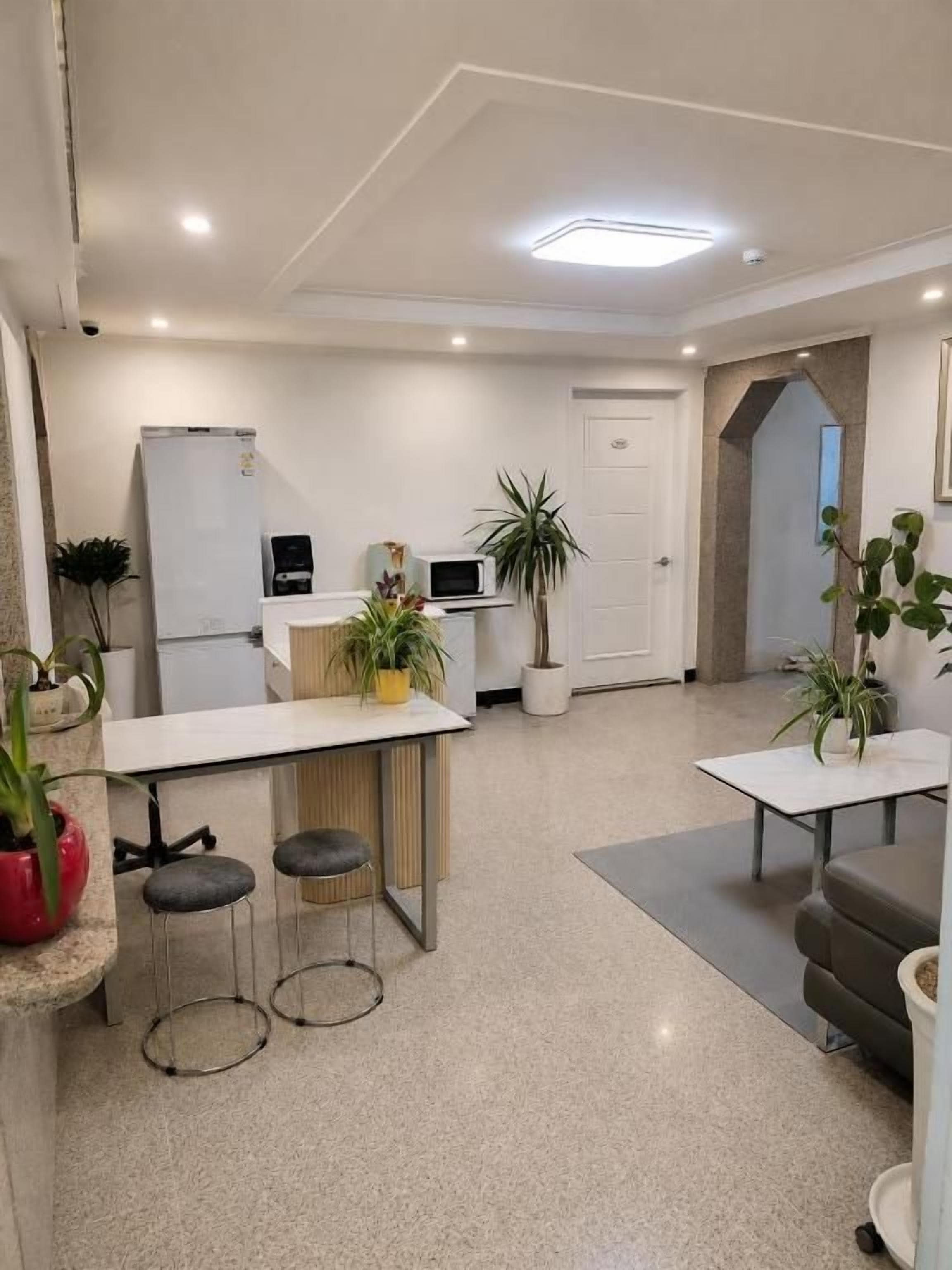 A modern kitchen with a refrigerator, microwave, and a small dining area with stools.