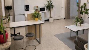 Una cocina moderna con refrigerador, microondas y un pequeño comedor con taburetes.