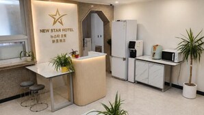 Un área de recepción de hotel con diseño moderno, que incluye un mostrador de recepción, una zona de estar y una kitchenette.