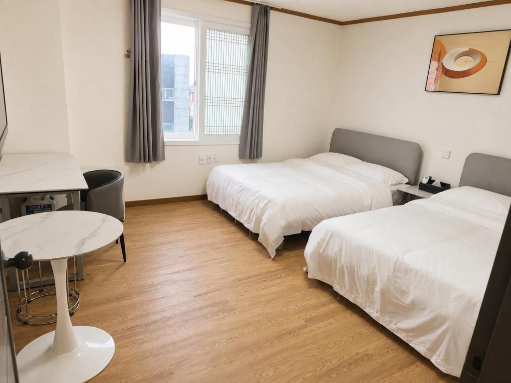 A hotel room with two beds, a desk, and a window with curtains.