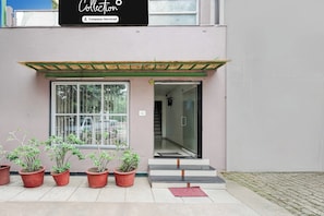 A building entrance with a glass door, potted plants, and a sign above. - Collection O Sachivalaya Metro Station (Gandhinagar)