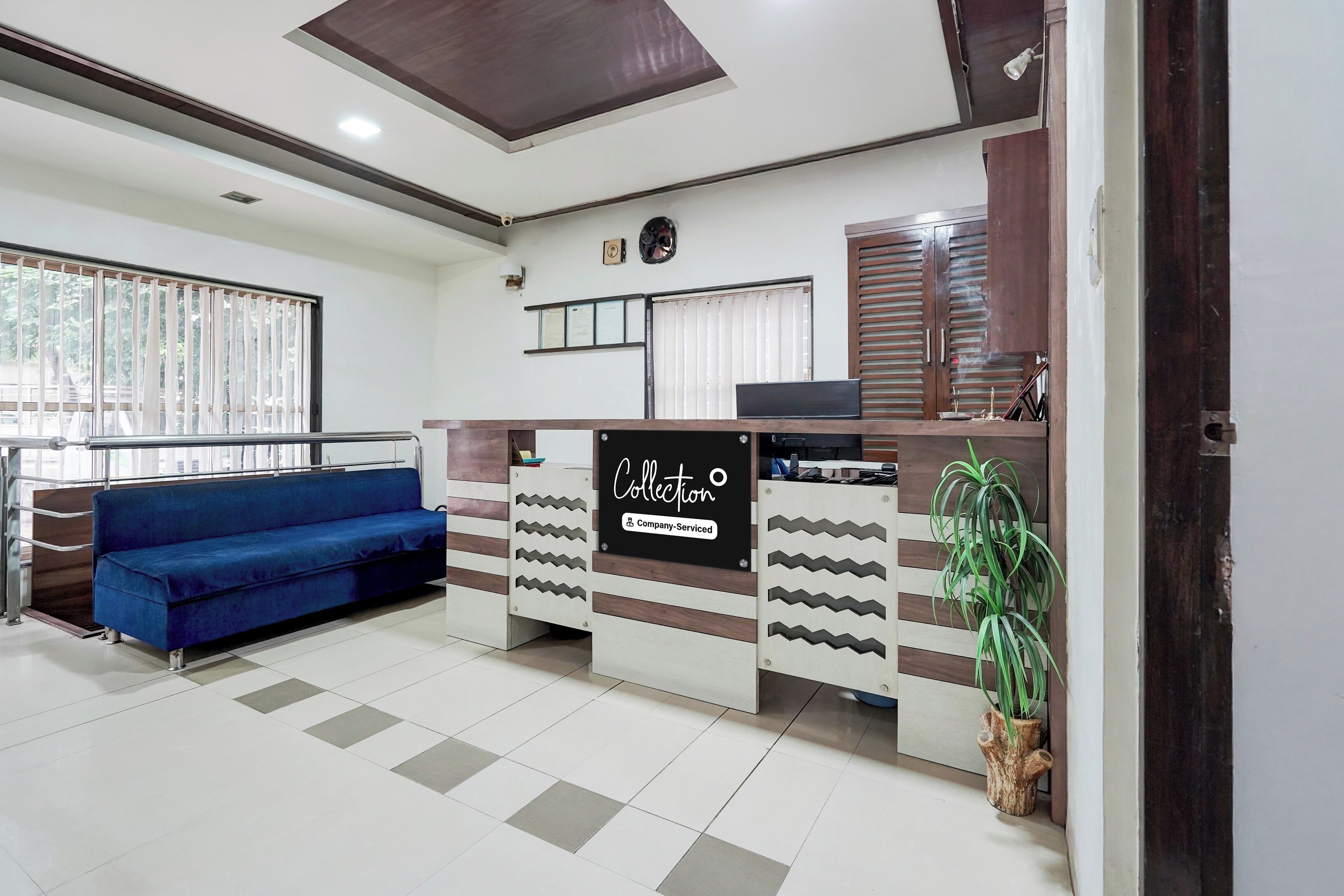 A reception area with a blue sofa, a reception desk, and a wall-mounted clock.