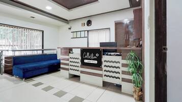 A reception area with a blue sofa, a reception desk, and a wall-mounted clock.