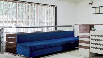 A room with a blue sofa, a metal railing, and a window with vertical blinds.
