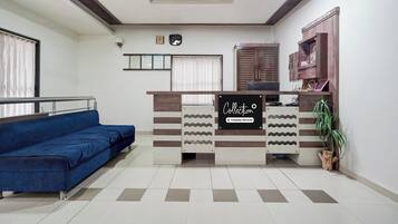 Un área de recepción con un sofá azul, un mostrador y un mueble de pared.