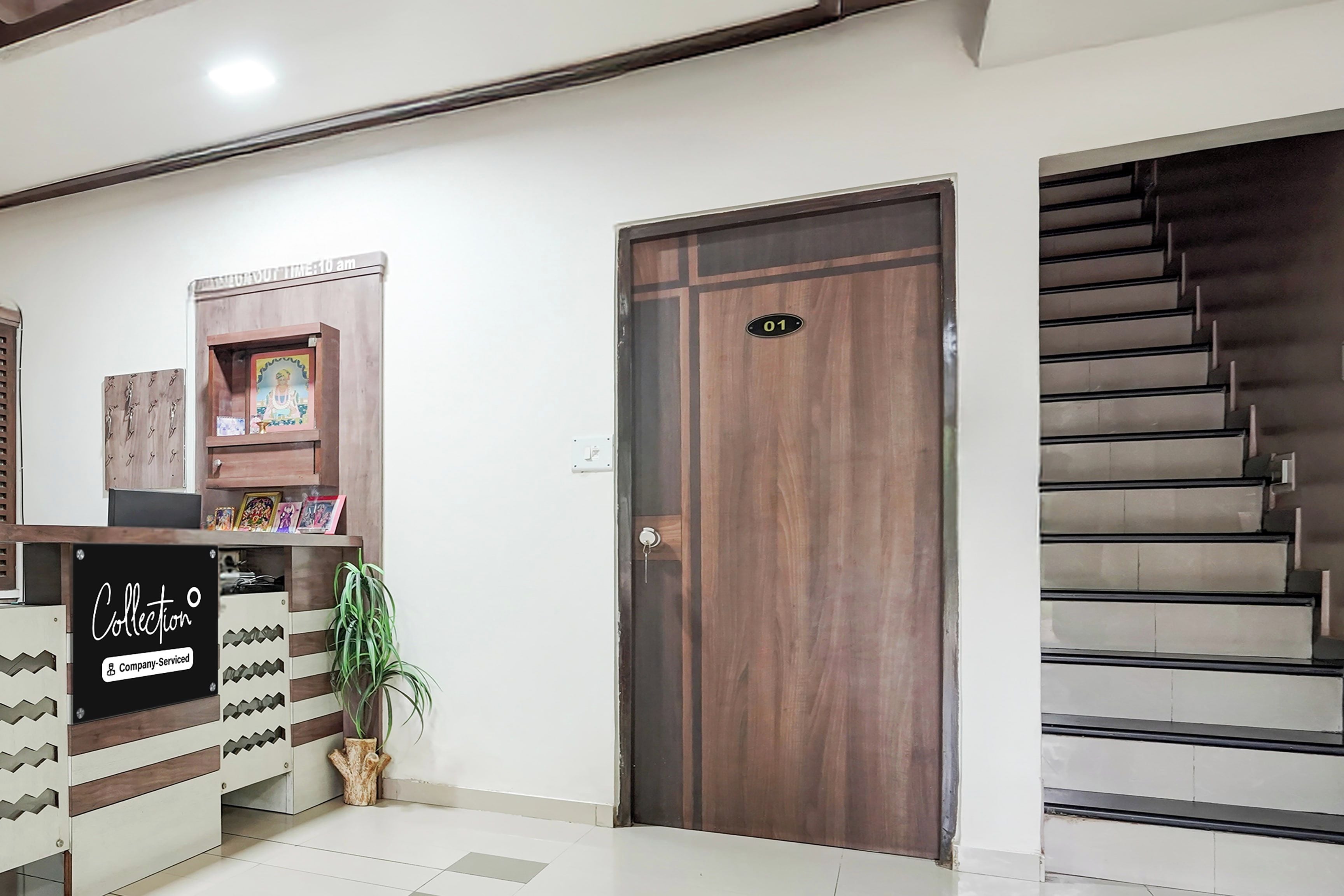 A reception area with a wooden door marked '01', a reception desk with a sign 'Collection Company-Serviced', and a staircase to the right.