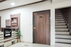 A reception area with a wooden door marked '01', a reception desk with a sign 'Collection Company-Serviced', and a staircase to the right.