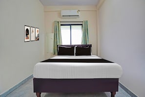 Ein Schlafzimmer mit einem Bett, einer Klimaanlage, einem Fenster mit Vorhängen und Wandbildern.