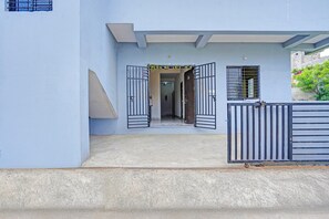 A building entrance with a gated driveway, a visible door, and a small window with bars.