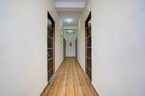 Un pasillo con suelo de madera, paredes blancas y puertas a ambos lados.
