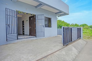 A modern building with a concrete entrance, metal gates, and a wooden door.