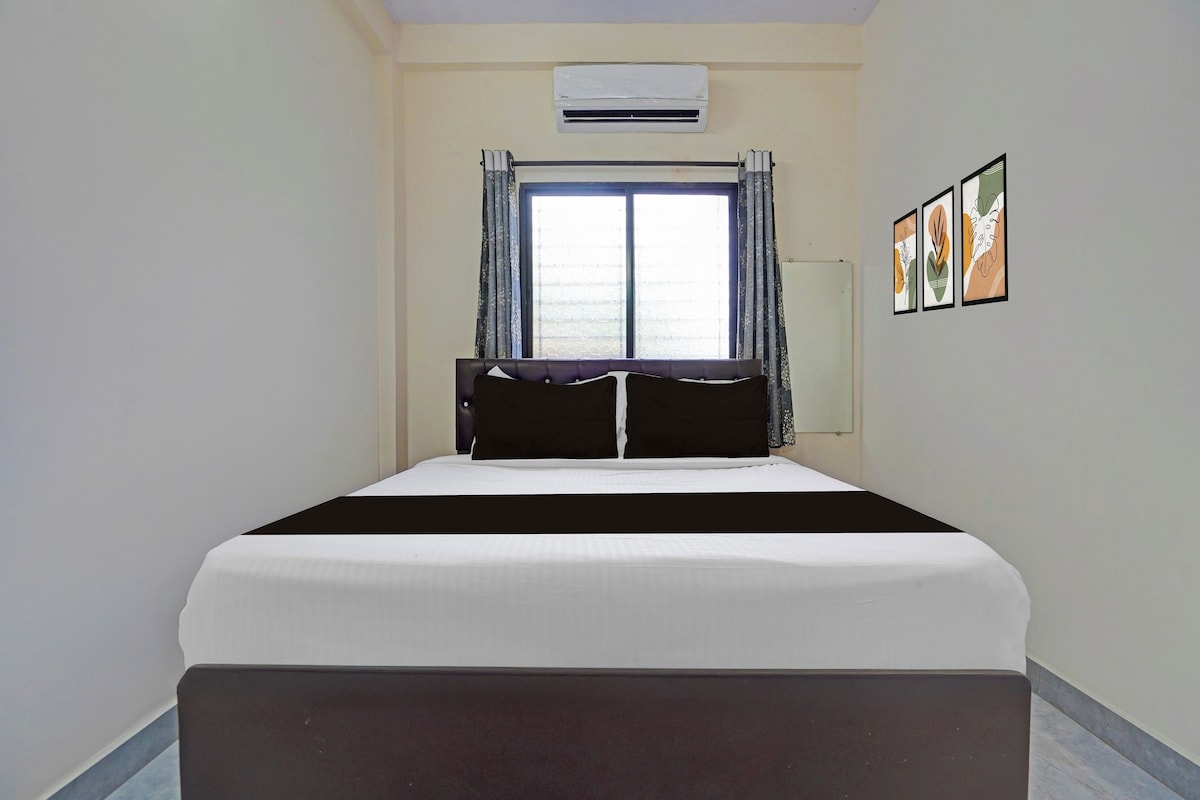 Ein Hotelzimmer mit Bett, Klimaanlage, einem Fenster mit Vorhängen und Wandbildern.