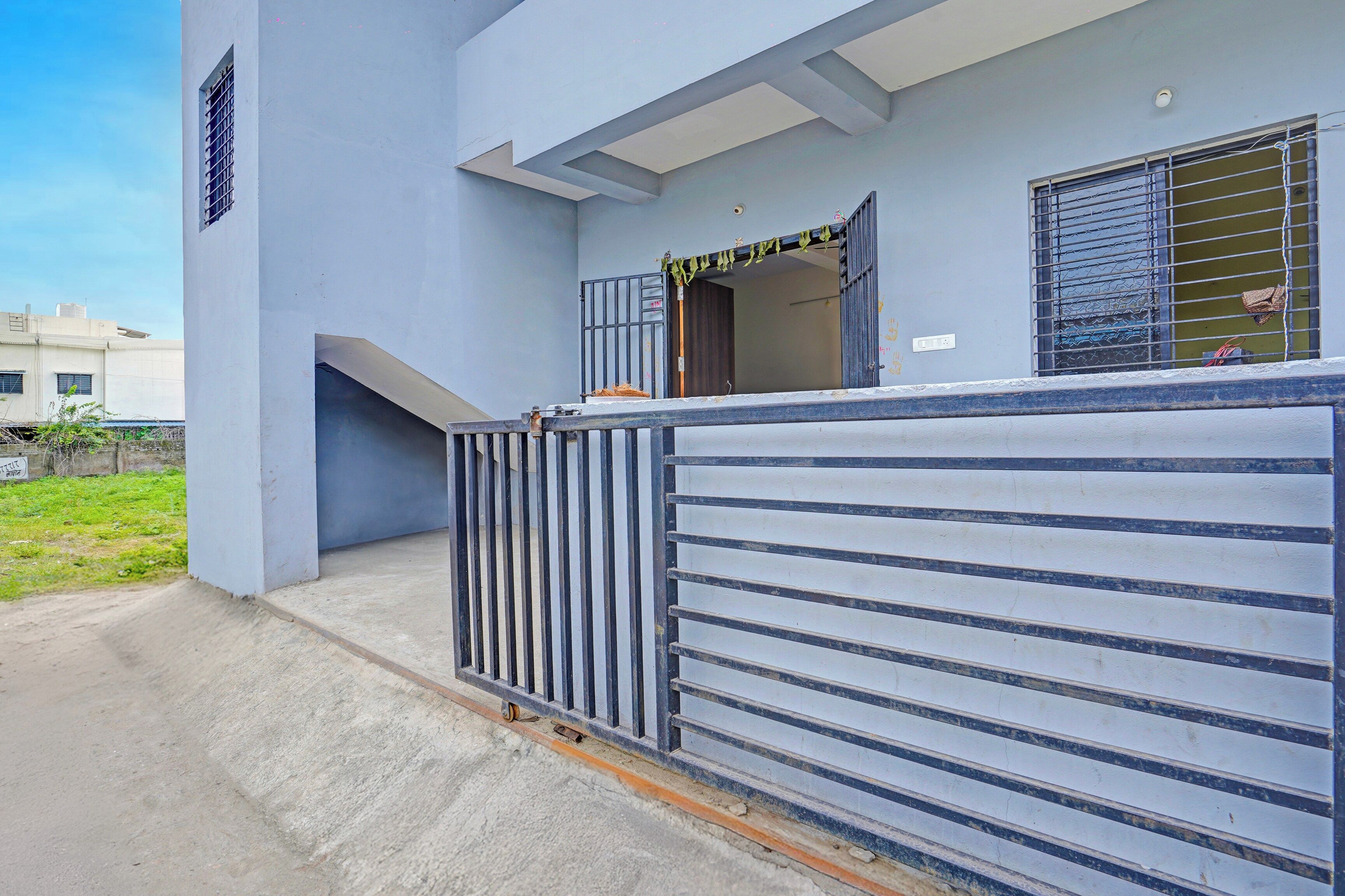A building with a gated entrance, a visible door, and a window with a metal grille.
