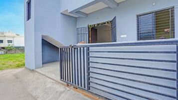 A building with a gated entrance, a visible door, and a window with a metal grille.