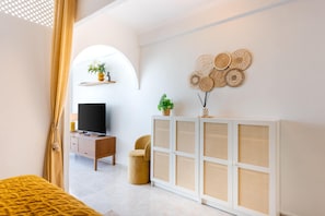 A modern living room with a TV, sofa, and decorative items. - Al Andalus Torremolinos – Bright Coastal Apartment near La Carihuela, Restaurants & Centre (Torremolinos)