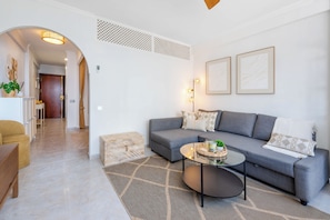 Een moderne woonkamer met een grijze bank, een salontafel en een kamerbreed tapijt met een patroon.