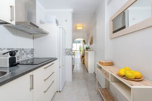 A modern kitchen with a built-in espresso machine, a refrigerator, and a counter with lemons. - Al Andalus Torremolinos – Bright Coastal Apartment near La Carihuela, Restaurants & Centre (Torremolinos)