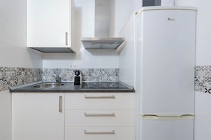 A kitchen with white cabinets, a stainless steel sink, a black kettle, and a white refrigerator. - Al Andalus Torremolinos – Bright Coastal Apartment near La Carihuela, Restaurants & Centre (Torremolinos)
