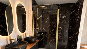 A modern bathroom with a black marble vanity, gold fixtures, and a glass-enclosed shower. - Cottage 'L’échappée Bleue De Marguerite' with private pool, terrace and Wi-Fi (Évron)