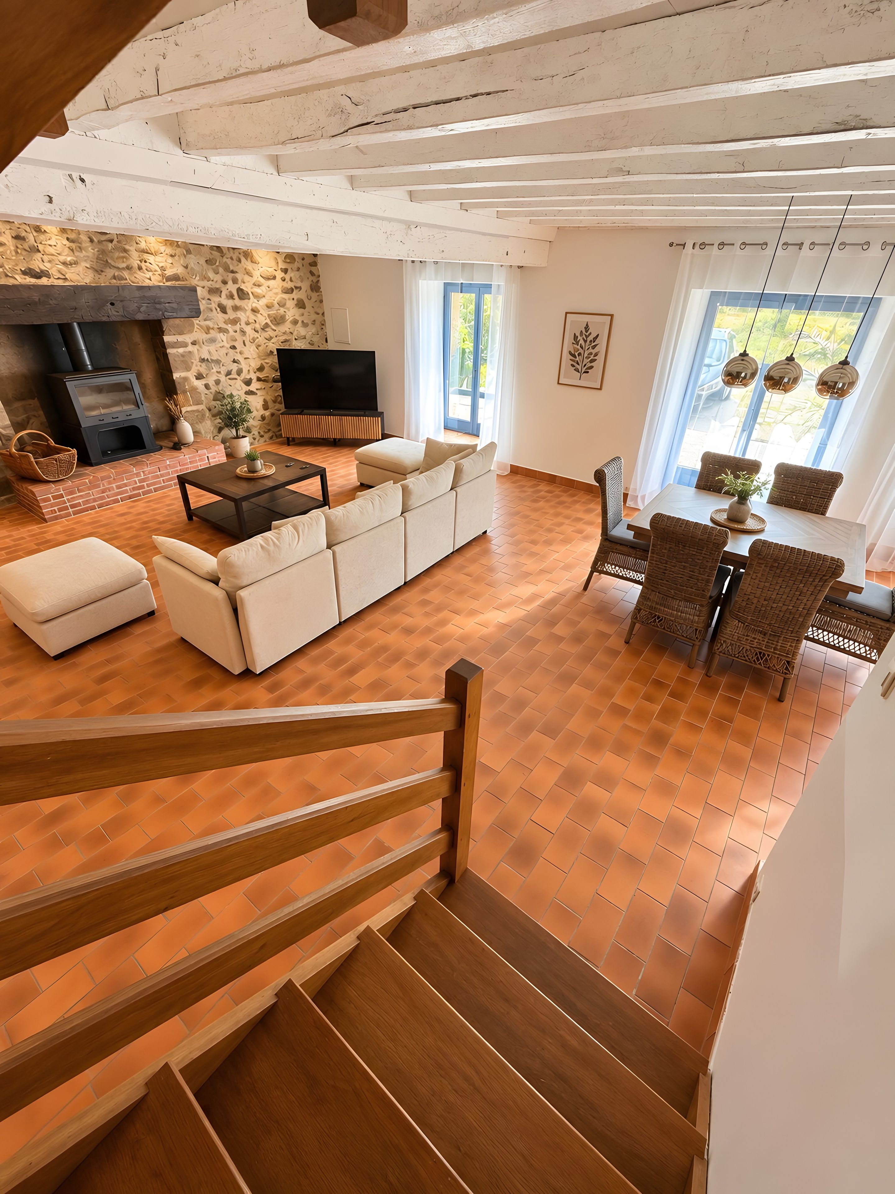 Amplia sala de estar con chimenea, un sofá, una mesa de comedor y una escalera.