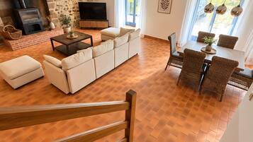 Amplia sala de estar con chimenea, un sofá, una mesa de comedor y una escalera.