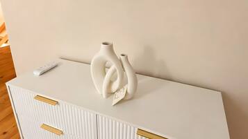 Een witte kast met gouden handgrepen en een witte vaas erop.