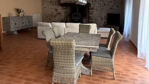 A dining area with a rustic stone wall, a fireplace, and a modern chandelier. - Cottage 'L’échappée Bleue De Marguerite' with private pool, terrace and Wi-Fi (Évron)
