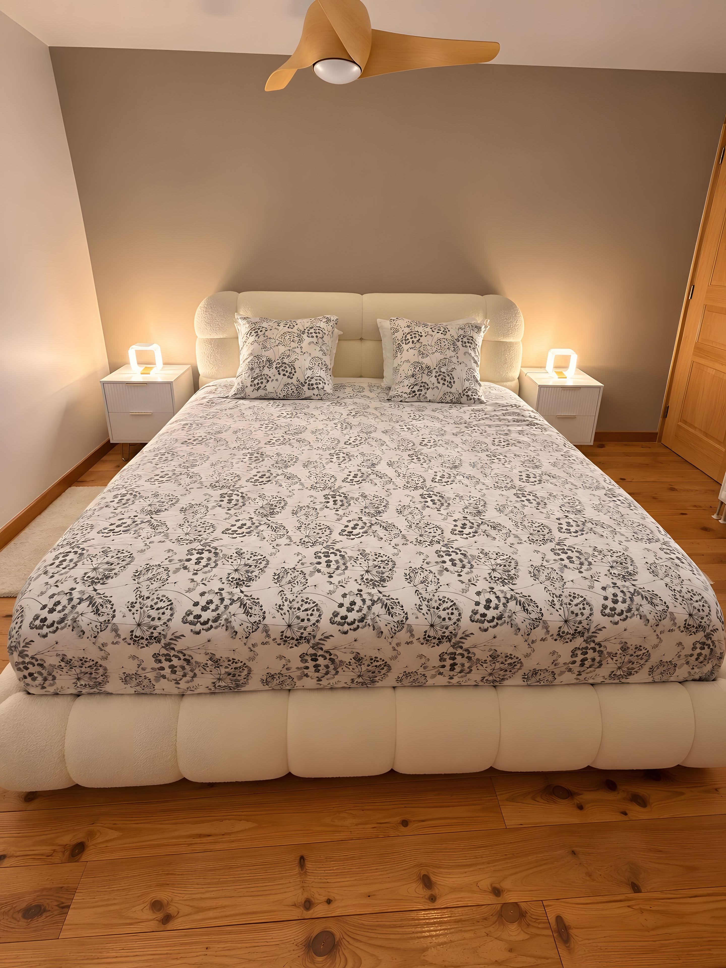 Une chambre à coucher avec un lit, deux tables de chevet avec des lampes, un ventilateur de plafond et un plancher en bois.